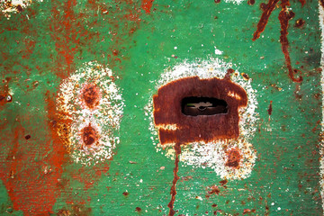 Rusty keyhole in a metal grunge green door