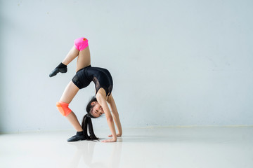 Fototapeta na wymiar Little ballerinas doing exercises and bending sitting on floor in ballet class.