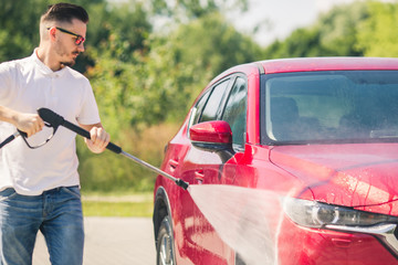 Manual car wash with pressurized water in car wash outside. Summer Car Washing. Cleaning Car Using...