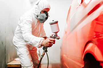 close up details of industrial worker, mechanic engineer using a paint gun and painting a car
