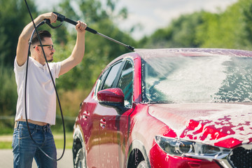 Manual car wash with pressurized water in car wash outside. Summer Car Washing. Cleaning Car Using...