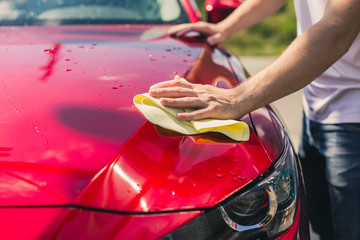 Car detailing - the man holds the microfiber in hand and polishes the car. Selective focus. Car...