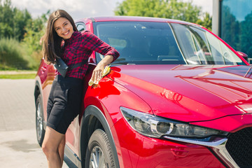 Car detailing - the female holds the microfiber in hand and polishes the car. Selective focus. Girl cleaning red car 2018