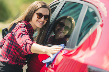 Car detailing - the female holds the microfiber in hand and polishes the car. Selective focus. Girl cleaning red car 2018