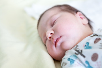 Head of infant with closed eyes, baby sleep on bedsheet