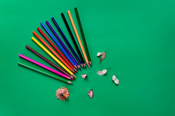 School colored pencils on a paper dark green background.School supplies