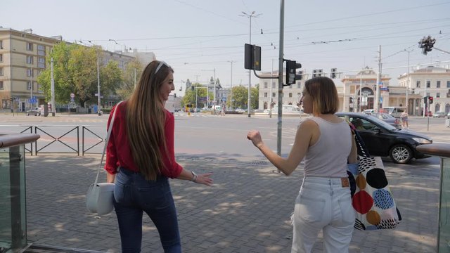 Two young pretty women friends saying goodbye kiss cheek after walk together in city