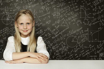 Cute smart child student girl on blackboard background with scie