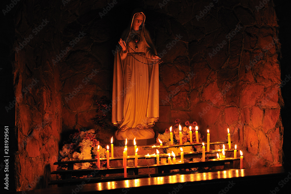 Wall mural altar with lit candles in a catholic church. the figure of the holy virgin mary.