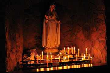 Altar with lit candles in a catholic church. The figure of the holy virgin Mary.