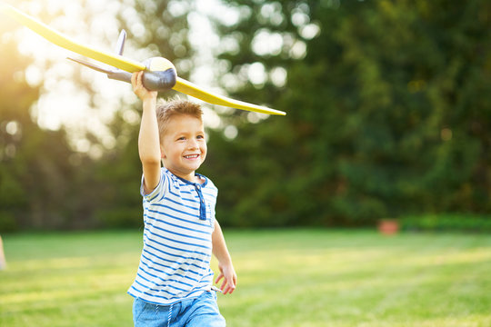 Happy 3 year old boy having fun playing with big plane outdoors