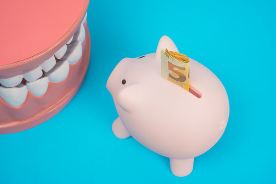 denture and piggy bank with money on blue background