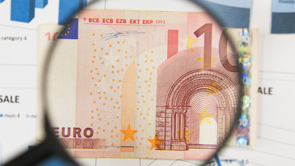 Close-up of ten euros through a magnifying glass. Business background. Money research concept.