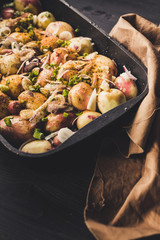 Baked potatoes with onions, garlic and spices on a dark rustic background. Vertical shot