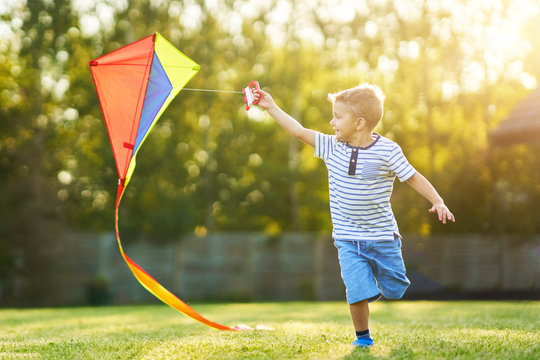 Happy 3 year old boy having fun playing with kite