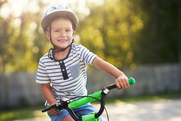 Obraz premium Happy 3 year old boy having fun riding a bike