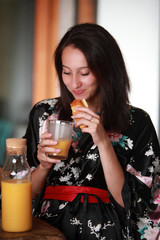 Jeune femme en peignoir prenant son petit déjeuner