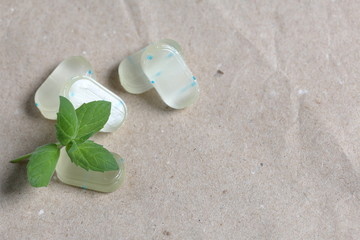 Peppermint candies for breath freshening. With refreshing microgranules. Cooling menthol for sore throat. Nearby are fresh mint leaves. On the background of crumpled wrapping paper.