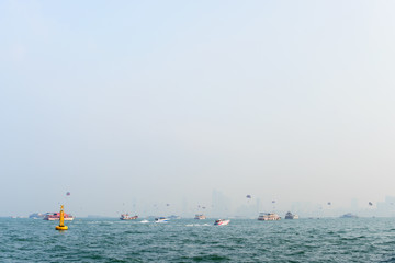 Sea sports in Pattaya, Thailand. Various boats and ships in the sea in front of city view on the horizon.