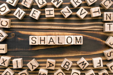 Shalom - word from wooden blocks with letters, Jewish greeting or saying goodbye concept, random letters around, top view on wooden background