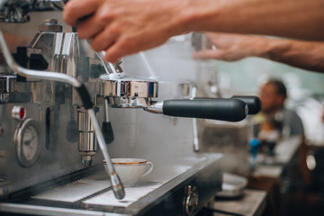 Coffee machine pouring coffee into white coffee cup.
