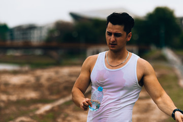 Portrait of sporty male runner holding mineral water at the break after running