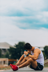 Young man in sleeveless holding fitness bottle with water