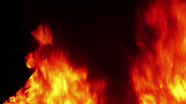 Huge Fire With Black Smoke is a beautiful stock video that features a close-up shot of a huge fire with golden flames and black smoke rising against an isolated black background. 