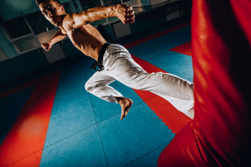 Male boxer training is exercising with a punching bag at the gym club.