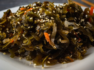 Seaweed salad with sesame seeds is on a white plate