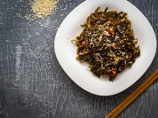 Seaweed salad with sesame seeds is on a white plate