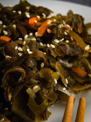 Seaweed salad with sesame seeds is on a white plate