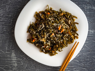 Seaweed salad with sesame seeds is on a white plate