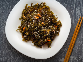 Seaweed salad with sesame seeds is on a white plate