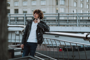 Calm young man on the bridge having phone talk