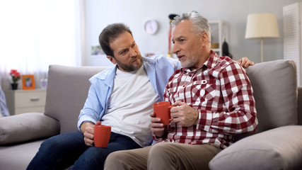 Father and son having coffee together, remembering pleasant moments, family