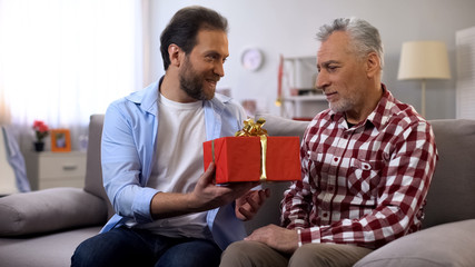 Adult son congratulating senior dad with fathers day, celebrating birthday, care