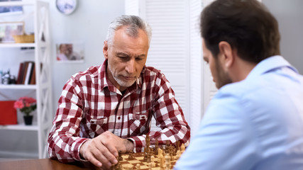 Serious senior male playing chess with opponent, complicated competition, sport