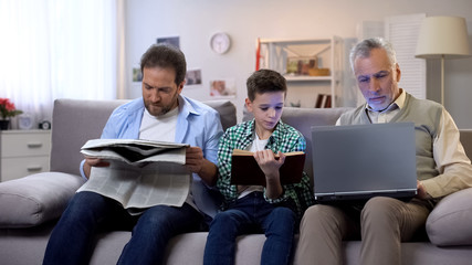 Dad and son reading book and newspaper, aging man holding laptop, generations