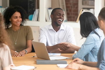Obraz premium Cheerful african businessman shaking hand business partner at meeting