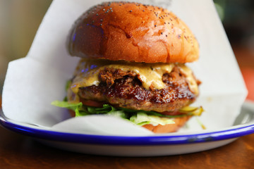 Juicy beef burger with cheese and herbs on a plate. Close-up