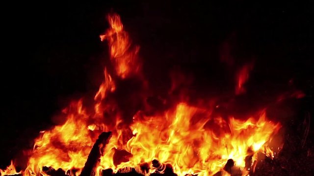 Huge Fire With Black Smoke is a beautiful stock video that features a close-up shot of a huge fire with golden flames and black smoke rising against an isolated black background. 