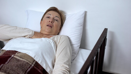 Sick female in bed hardly breathing, suffering suffocation, asthma disease