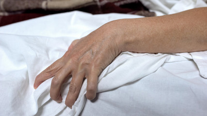 Sick female hand clenching bedsheets, suffering strong pain, terrible cramps