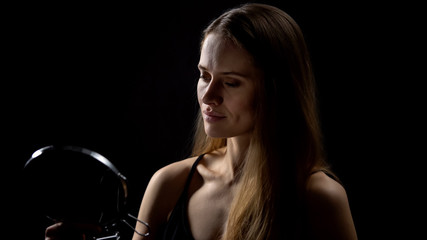 Exhausted woman looking in mirror, isolated on black background, cosmetology
