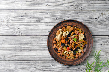 set of dried fruits and nuts on a clay plate top view.
