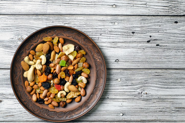 set of dried fruits and nuts on a clay plate top view.