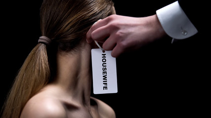 Male hand putting housewife label on female ear, indicating place of women