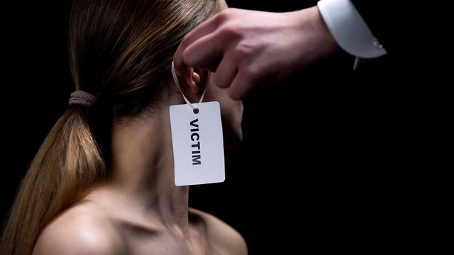 Male Hand Putting Victim Label On Female Ear, Humiliation And Bullying, Close-up