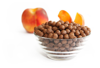 sweet chocolate corn balls in glass plate and peach on a white background